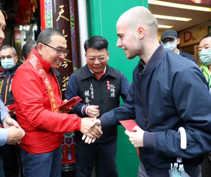 《​圖說》侯友宜於慈惠宮親發馬年福袋分享喜氣，吸引外國友人排隊體驗台灣道地年味。〈民政局提供〉