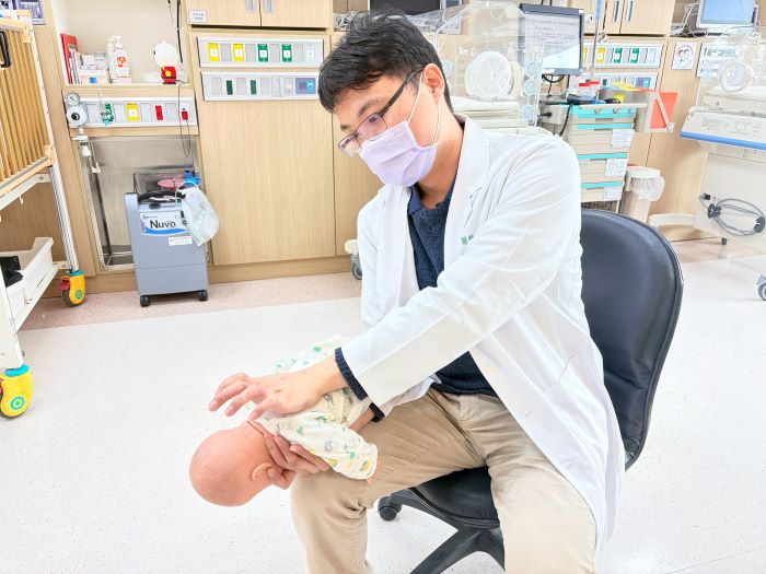 《圖說》邱俊哲醫師示範一歲以下嬰兒「拍背壓胸法」，背部拍擊5次、正面壓胸5次，反覆進行至異物排出。〈土城醫院提供〉