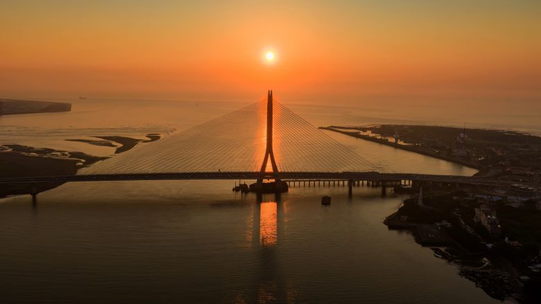 《圖說》淡水河口的金黃夕照與宏偉的淡江大橋巧妙相遇，橋塔的俐落剪影與波光 粼粼的水面勾勒出專屬淡八地區的嶄新觀光地標。〈觀旅局提供〉