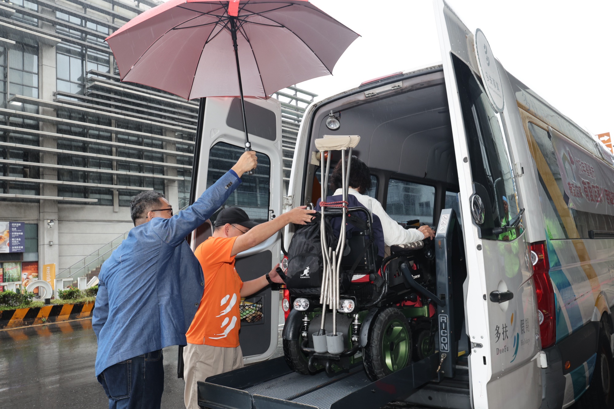 工作人員協助輪椅使用者登上無障礙車輛
