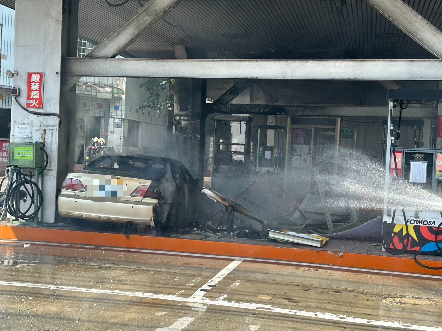 消防人員灌救加油站內的起火車輛