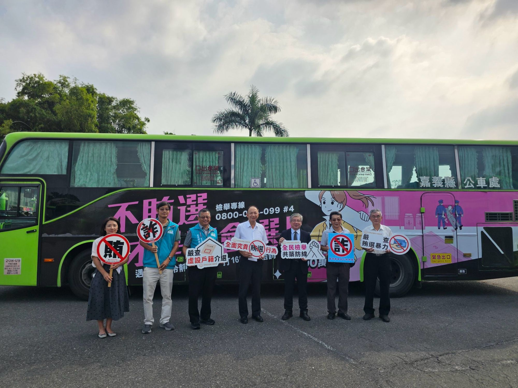 與會人員手持反賄選、反詐騙標語於廣告公車前合影