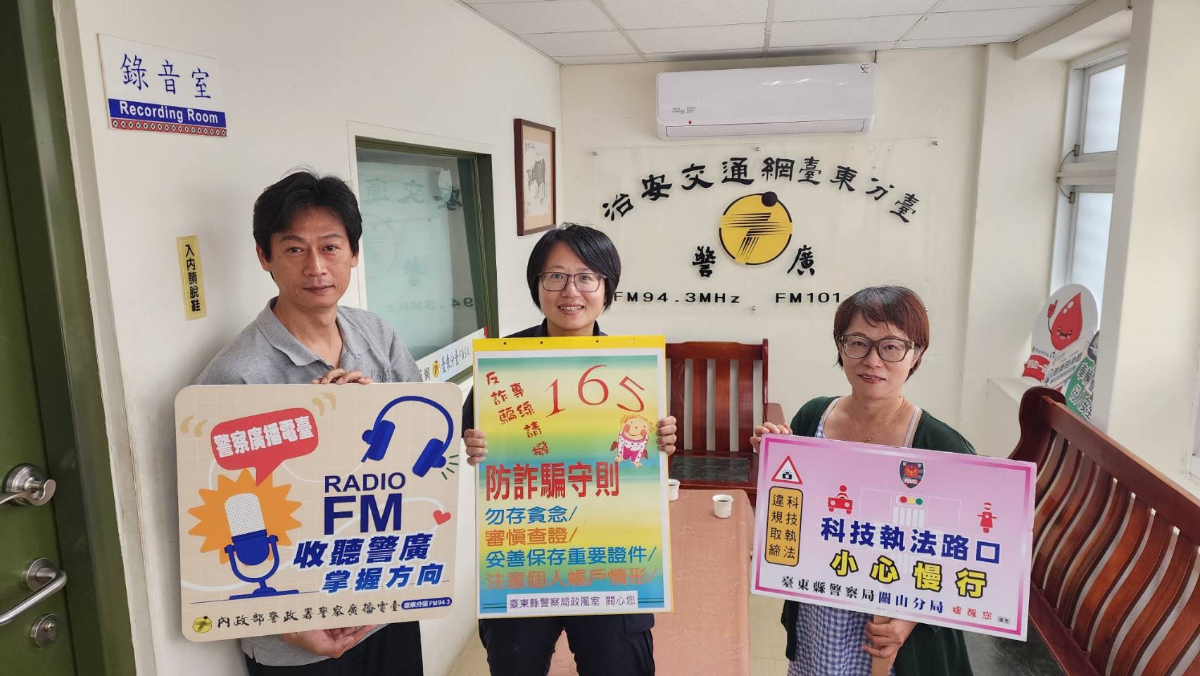 張瑋紋組長(中)與警廣臺東分臺人員手持防詐、交通安全宣導牌
