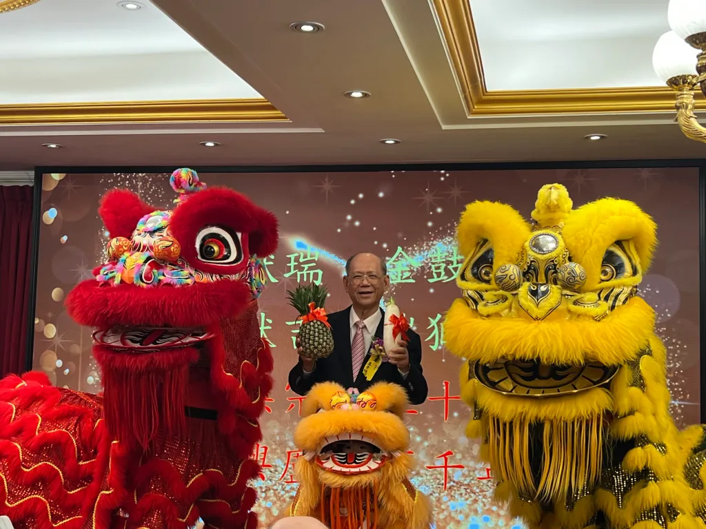 台北市盧氏宗親會50週年會慶，理事長盧景鎮（中）與祥獅合影，手持象徵吉祥的鳳梨與好彩頭，為慶典增添喜氣，寓意宗親會會務興隆、世代傳承。
